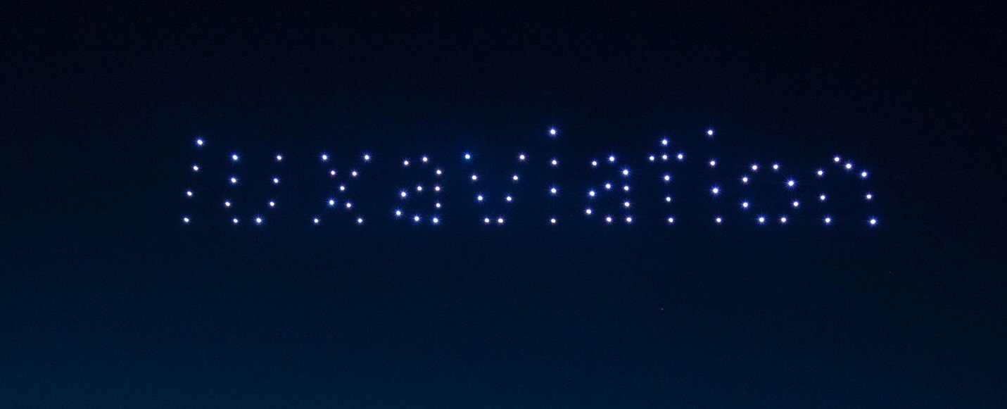 A night sky with "luxaviation" spelled out using small, bright lights.