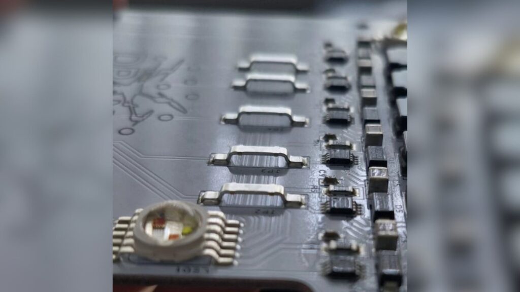 Close-up of an electronic circuit board showing resistors, microchips, and metallic connectors.